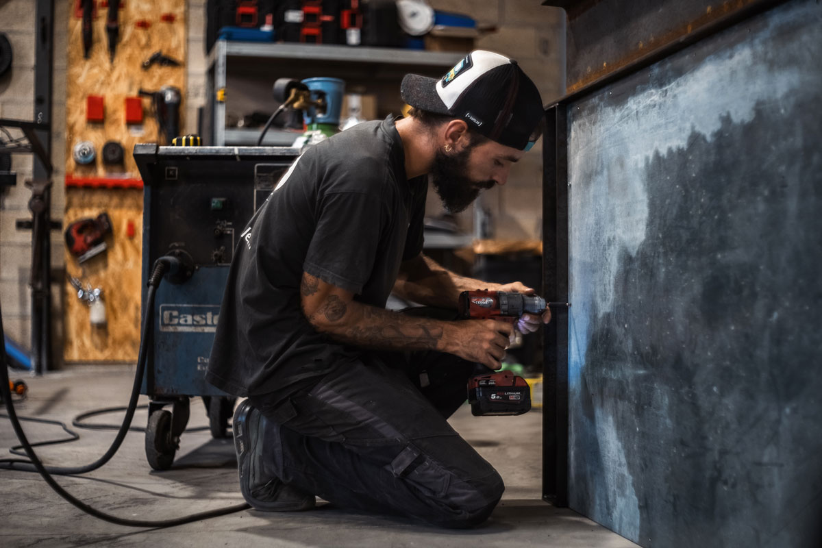 Un technicien soude l'intérieur d'une portière d'une voiture de collection